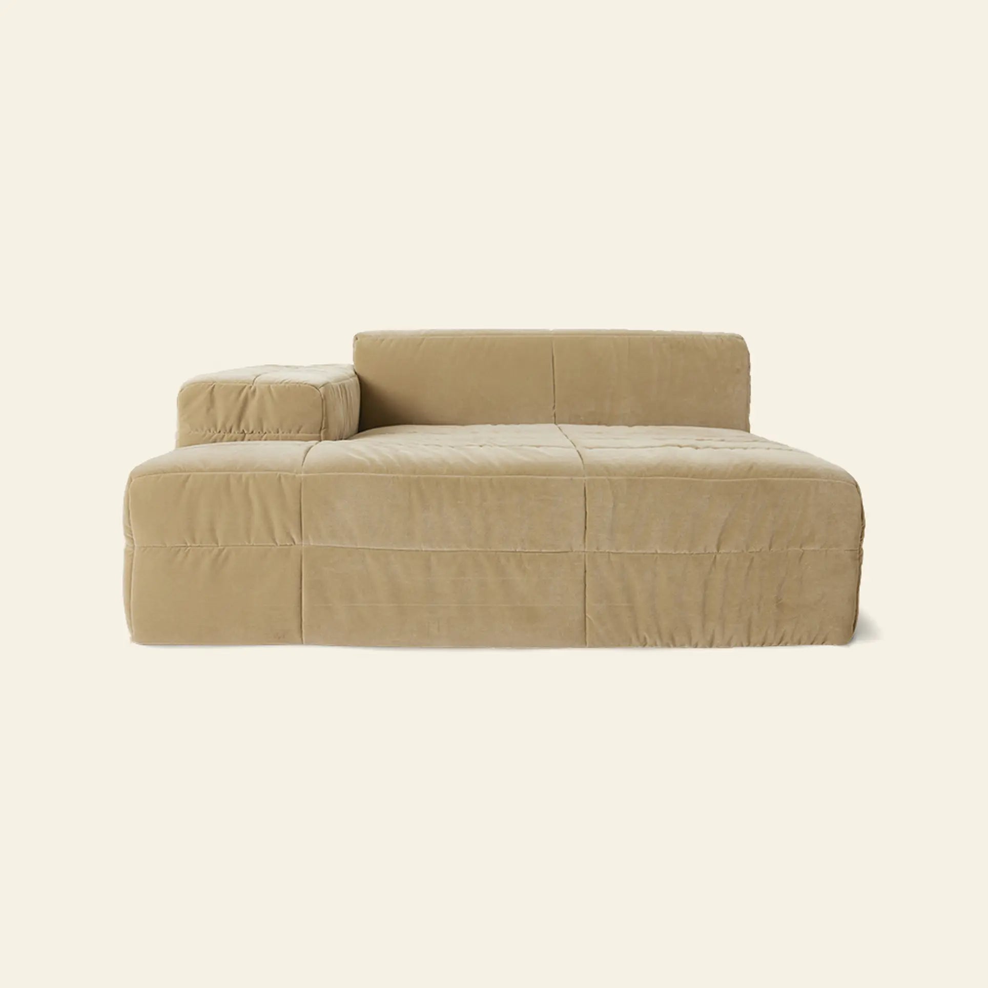 The HKLIVING Brut Sofa, Left Divan by HKLIVING is a beige, modern, low-profile piece with spacious seating, an attached left cushion, and clean boxy lines—offering sculptural design set against a plain, light background.