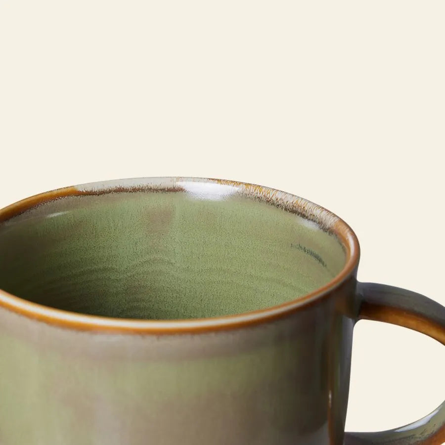 A close-up of the HKLIVING Chef Ceramics: Mug by HKLIVING, featuring a green finish with a brown rim and handle, set against a plain light beige background.
