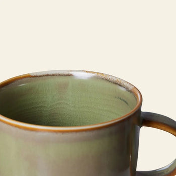 A close-up of the HKLIVING Chef Ceramics: Mug by HKLIVING, featuring a green finish with a brown rim and handle, set against a plain light beige background.