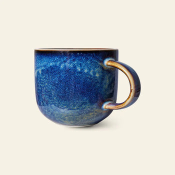 The HKLIVING Chef Ceramics: Mug by HKLIVING features a rounded shape, blue and indigo speckled glaze, a brown-tinted handle, and unique hand-glazed details set against a plain light background.