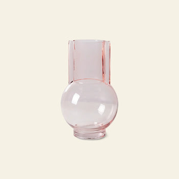 The HKLIVING Glass Vase Sundae Pink by HKLIVING features clear, light pink glass with a round base and tall cylindrical neck, ideal for contemporary decor. It is displayed against a plain beige background.