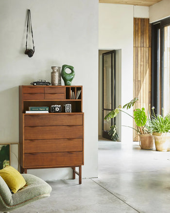 An HKLIVING HK Objects: Ceramic Sculpture by HKLIVING sits atop a mid-century wooden dresser against a white wall, surrounded by vintage cameras, interior decor, and a toy car. Green plants and sunlight from large windows complete the scene.