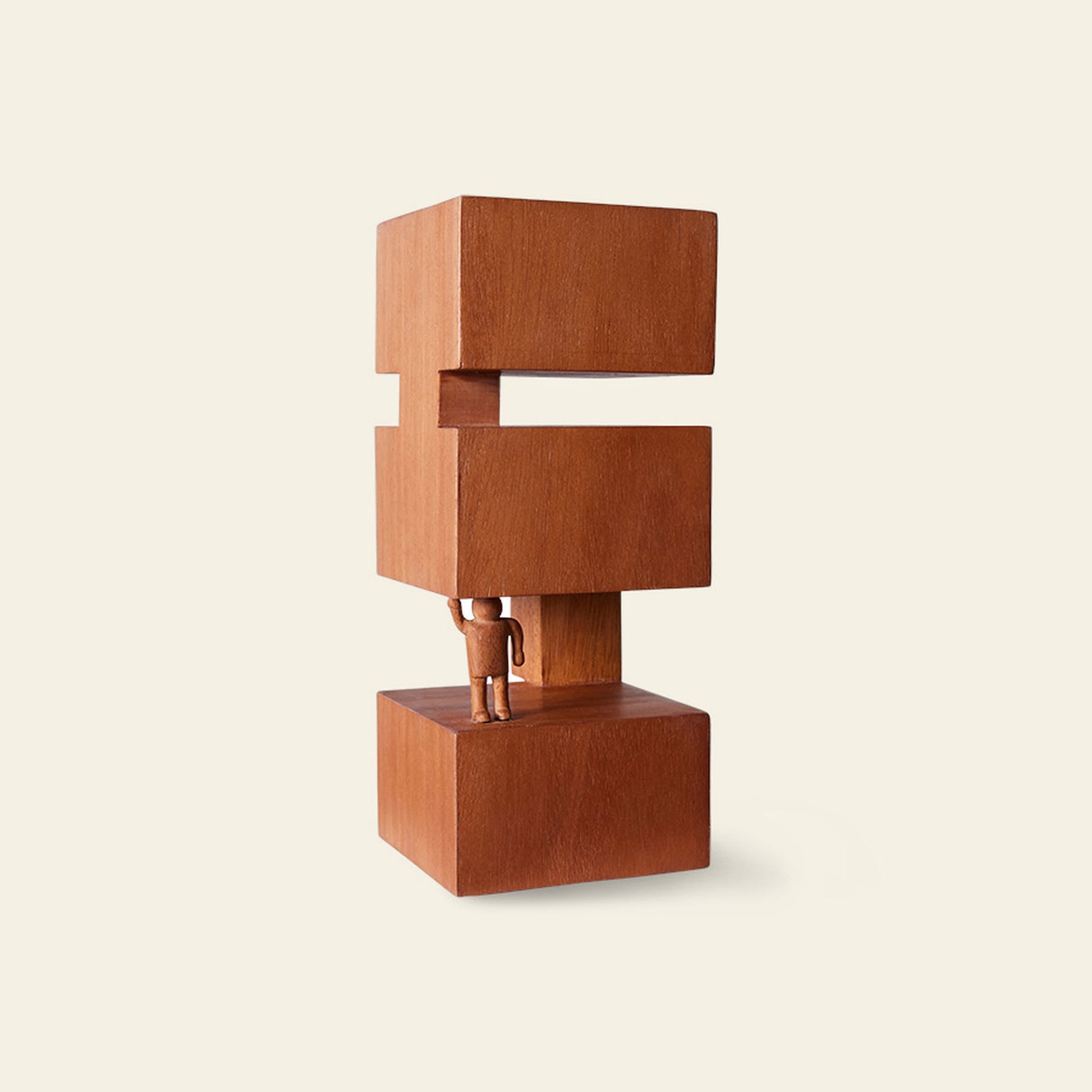 A small human figure lifts a large geometric wooden sculpture of three stacked blocks with a gap, set against a plain beige background. The HKLIVING HK Objects: Empowered by HKLIVING is perfect Bauhaus-inspired art for modern interiors.