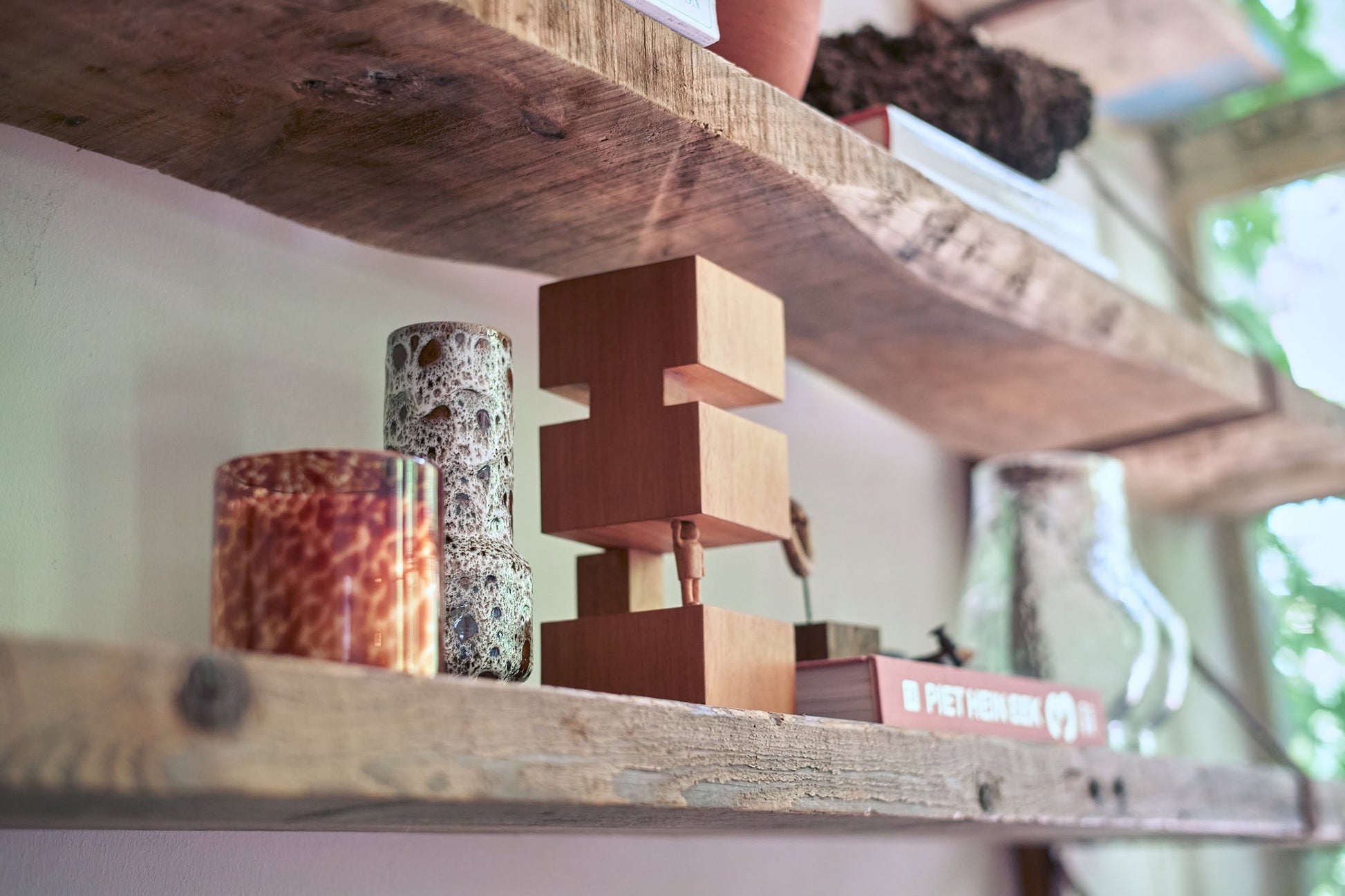 HKLIVING's HK Objects: Empowered display decorative objects on rustic wooden shelves—a speckled glass candle, sculptural art, patterned vase, and book by a sunlit window—perfect accents for modern interiors.