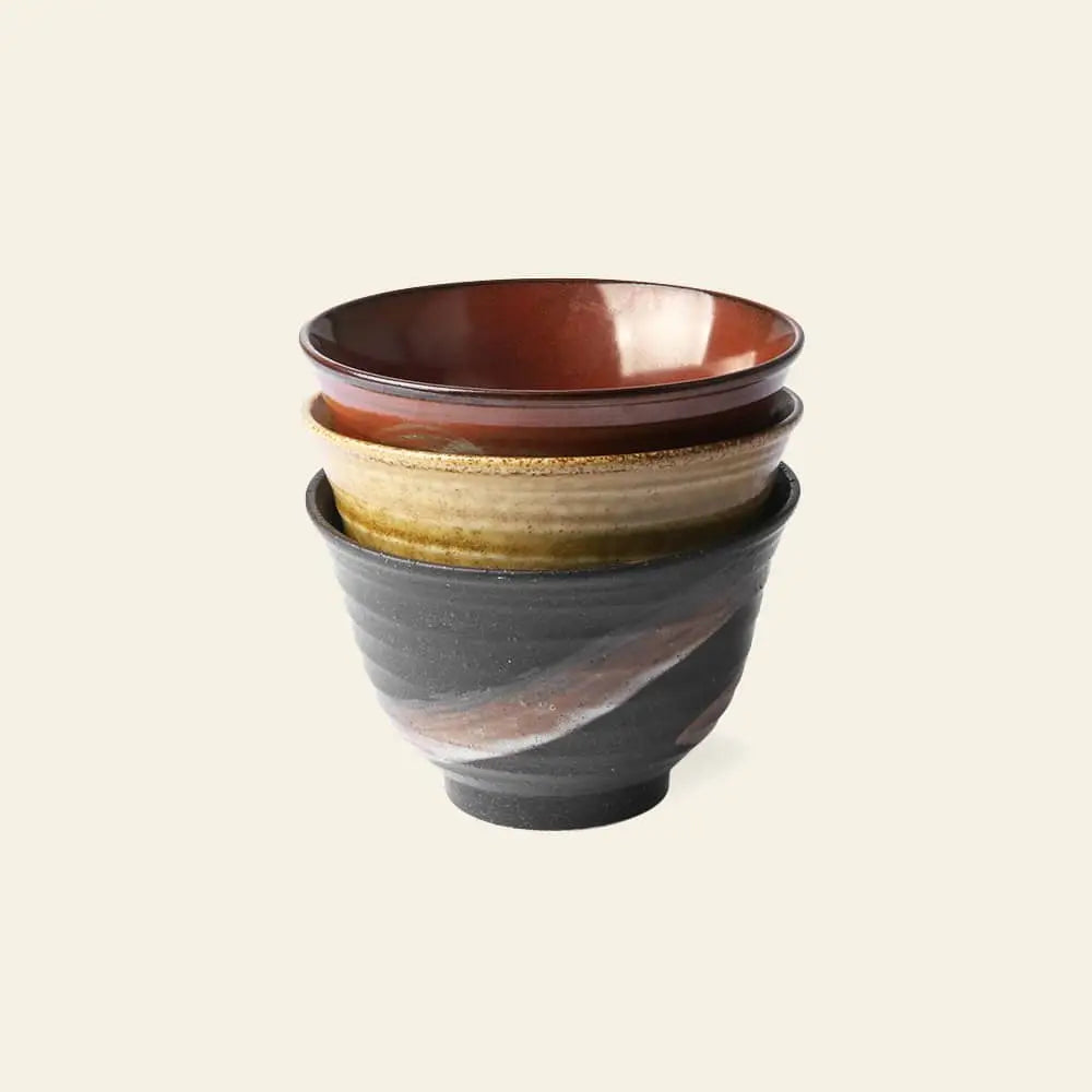 The HKLIVING Kyoto Ceramics Set features three hand-finished Japanese matcha bowls, each with a unique glaze: reddish-brown on top, glossy tan in the middle, and swirling dark gray at the bottom.