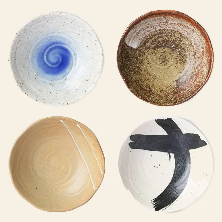 The HKLIVING Kyoto Ceramics Japanese Shallow Bowls set includes four uniquely designed bowls: white with a blue swirl, brown-speckled, beige with thin white lines, and white with a bold black brushstroke cross.