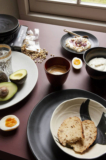 A breakfast spread with sliced avocado, a soft-boiled egg, bread, and yogurt with granola is served in HKLIVING Kyoto Ceramics Japanese Shallow Bowls (set of 4), beautifully arranged near a sunlit window alongside coffee and water.