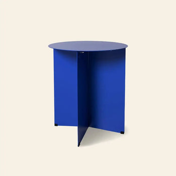 The HKLIVING Metal Side Table Round features a flat blue top and intersecting blue panel legs, adding a modern touch to classic side table design. Shown here set against a plain beige background.