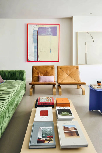A modern living room featuring a green sofa, two tan leather chairs, a beige coffee table with art books, the HKLIVING Metal Side Table Round by HKLIVING with a cup, and abstract art on white walls.