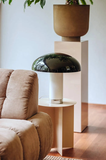 A modern living room with a beige corduroy sofa, an HKLIVING Metal Side Table Round holding a glossy black mushroom lamp, and a large brown plant pot on a pedestal in the background.