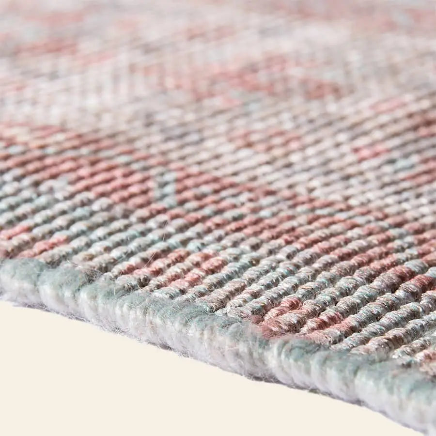 Close-up of the HKLIVING Printed Indoor/Outdoor Rug (120x180) by HKLIVING, showing its textured woven pattern in muted pink, blue, and beige on cream. Made from recycled PET bottles, eco-friendly weaving and fibers are clearly visible.