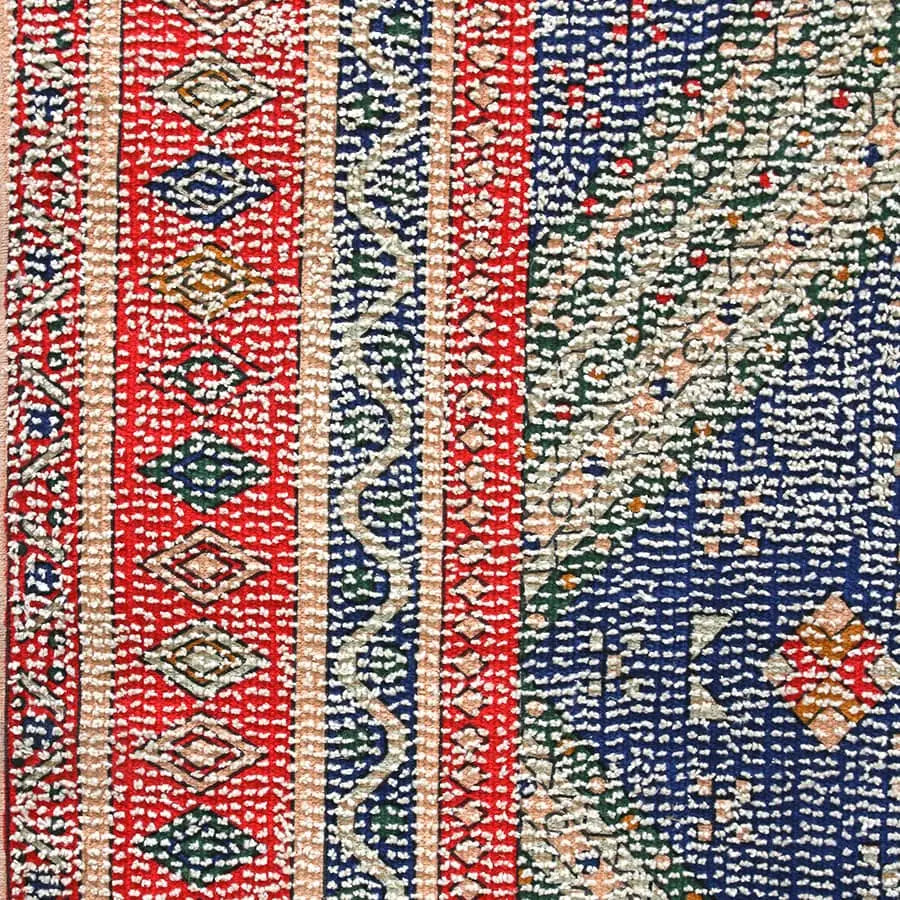 The HKLIVING Printed Rug Overtufted (150x240) by HKLIVING features vibrant red and blue geometric diamond and zigzag patterns, detailed embroidery in white, orange, and green, plus an anti-slip backing for safety.