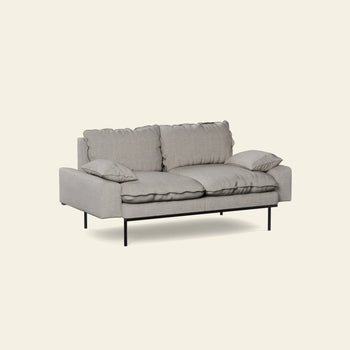 The HKLIVING Retro Sofa, 2-Seats, by HKLIVING features a vintage-inspired design in light gray with plush cushions, two matching throw pillows, and slim black metal legs, shown against an off-white background.