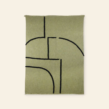 The HKliving Soft Woven Throw With Black Tufted Lines features a minimalist rectangular green design, bold black curved and straight lines, slightly fringed edges, and a cosy cotton-like texture, shown on a neutral background.