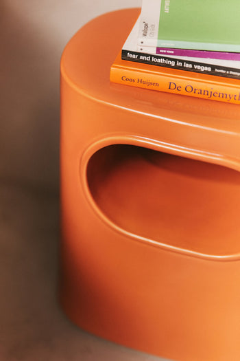 Close-up of the HKLIVING Space Side Table by HKLIVING, featuring a rounded cutout, built-in storage, and topped with books including Fear and Loathing in Las Vegas and De Oranjemythe by Coos Huijsen.