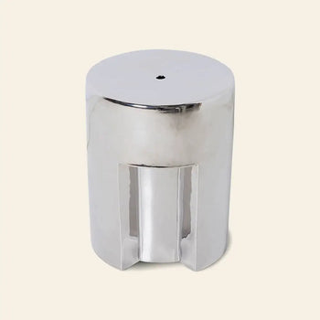 The HKLIVING Stoneware Side Table - Chrome by HKLIVING is a shiny, cylindrical side table with a smooth, reflective surface and a small round hole on top, shown against a light beige background.