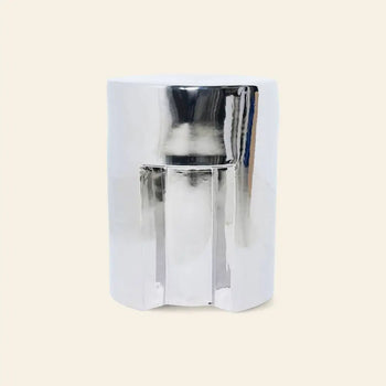 The HKLIVING Stoneware Side Table - Chrome by HKLIVING features a modern cylindrical design with a reflective metallic finish and subtly indented sides, shown against a plain beige background.