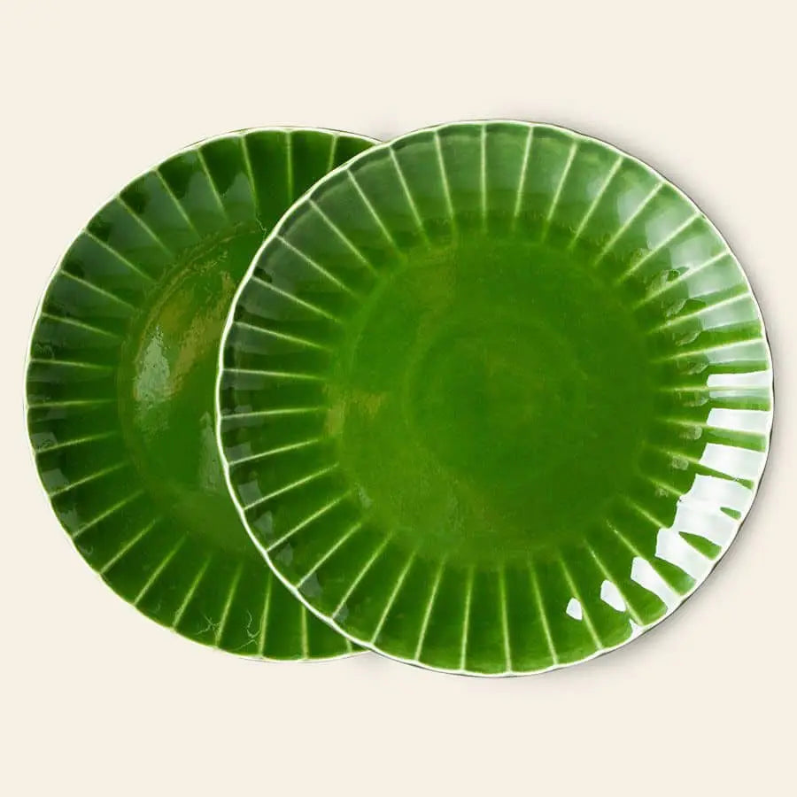 The HKliving The Emeralds: Ceramic Dinner Plate Ribbed, Set of 2 features glossy, emerald green plates with white rims and a fluted pattern. The ceramic plates overlap slightly against a plain, light background.