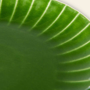 Close-up of the HKliving The Emeralds: Ceramic Dinner Plate Ribbed, Set of 2—an emerald green ceramic plate with a shiny finish and white radiating lines to a scalloped edge, set against a plain background. Brand: HKliving.