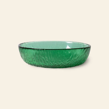 The HKliving The Emeralds: Glass Dessert Bowl, a round, shallow bowl with textured green glass, is shown on a light beige background, showcasing modern elegance.