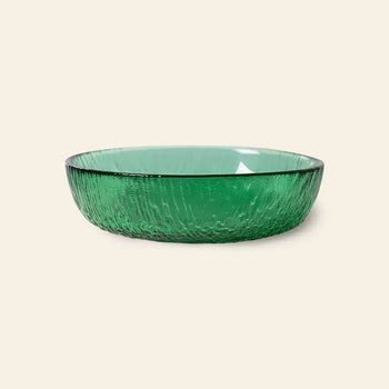 The HKliving The Emeralds: Glass Dessert Bowl, with its modern round design and textured green glass, brings contemporary elegance. Displayed on a light beige background, the bowl adds charm to any table setting.