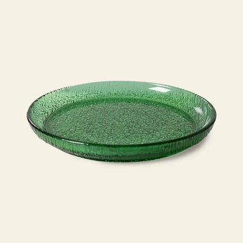 The HKliving The Emeralds: Glass Side Plate features a round, textured emerald green design with raised edges—ideal for stylish dinner parties. Displayed on a plain light background.
