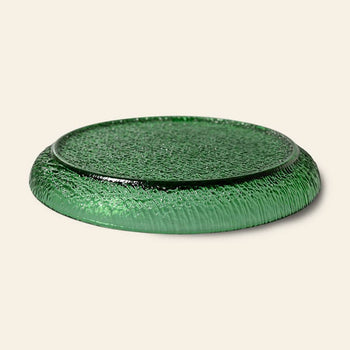 The HKliving The Emeralds: Glass Side Plate features an emerald green, textured design with slightly raised edges—ideal for stylish dinner parties. Shown against a light beige background.
