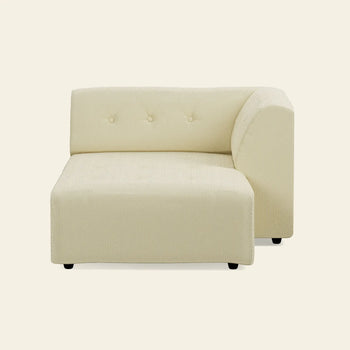 The HKLIVING Vint Couch, Right Divan by HKLIVING is a modern cream sofa with a rounded armrest and three button-tufted backrest details, shown on an off-white background. This customizable piece combines style and comfort.