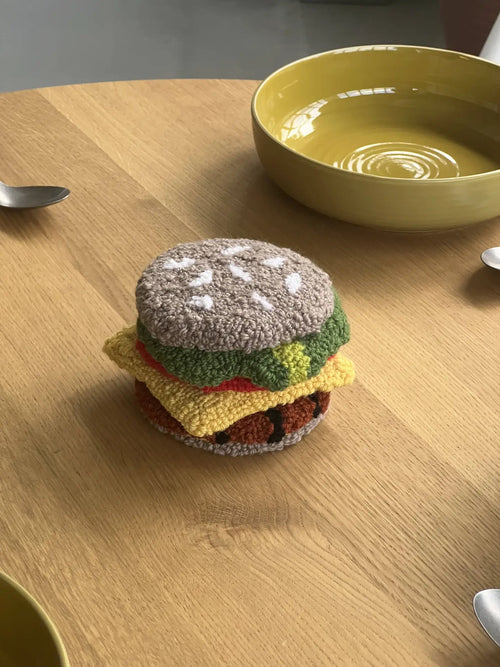 A set of Habichl Burger Coasters from Habichl rests on a wooden table, surrounded by three yellow bowls and three metal spoons.
