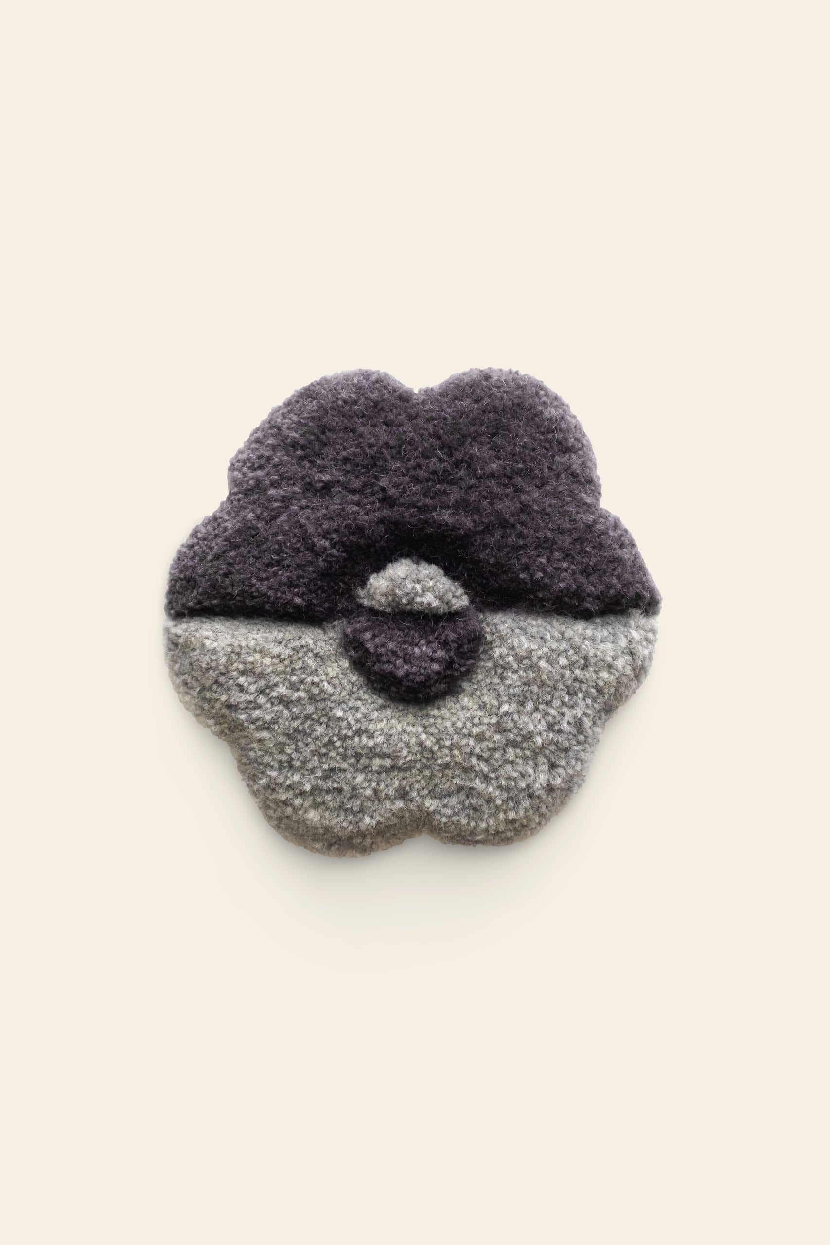 The Habichl Tufted Coasters by Habichl feature a textured, flower-shaped design with a thick, fluffy surface. The top half is dark purple, the bottom half is light gray, and the background is plain off-white.
