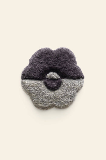 The Habichl Tufted Coasters by Habichl feature a textured, flower-shaped design with a thick, fluffy surface. The top half is dark purple, the bottom half is light gray, and the background is plain off-white.