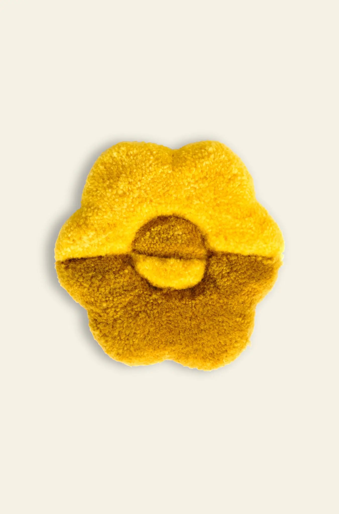 A plush, yellow Habichl Tufted Coaster by Habichl with a unique flower shape and central circular detail is displayed against a light beige background.