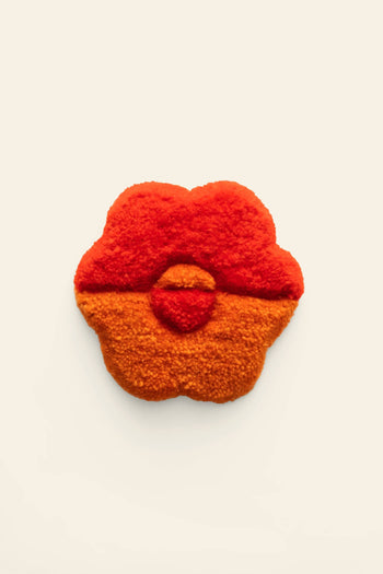 A handmade Habichl Tufted Coaster by Habichl, featuring a flower shape with a unique tufted design and fluffy texture, red on top and orange on the bottom, is showcased against a plain off-white background.