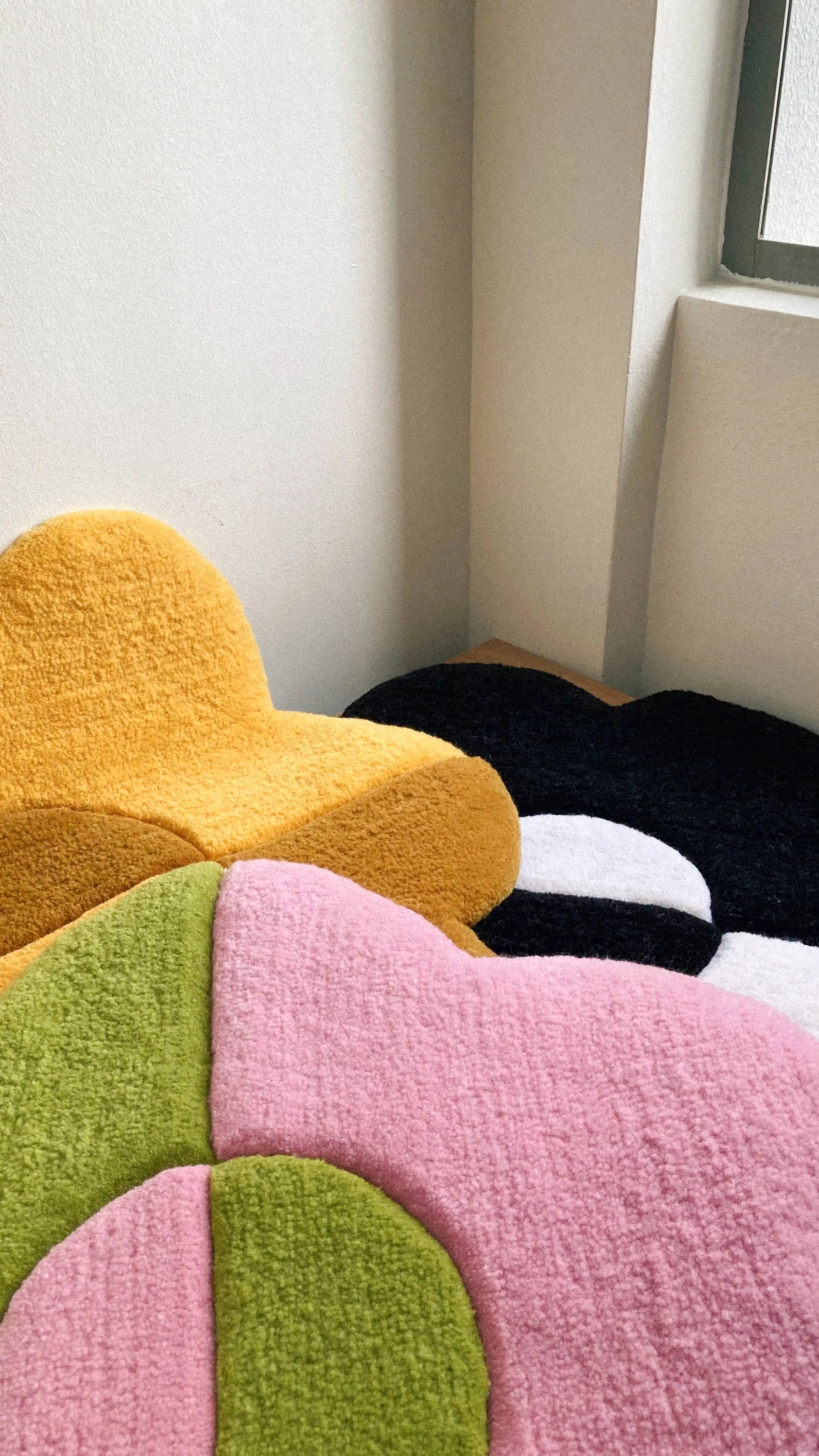 The Habichl Tufted Flower Floor Rugs by Habichl, available in yellow, black and white, green, and pink, add a whimsical touch to any room corner or window area.
