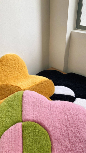 The Habichl Tufted Flower Floor Rugs by Habichl, available in yellow, black and white, green, and pink, add a whimsical touch to any room corner or window area.