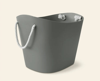 The Hachiman Balcolore Storage Basket M is a gray, flexible tub with a wavy rim and white rope handle, perfect for minimalist Japanese homes. Shown against a plain, light background.