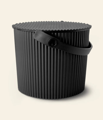 A black Hachiman Omnioutil Storage Bucket S with ribbed sides, a ridged lid, and sturdy handle for indoor or outdoor use, shown against a plain light background.