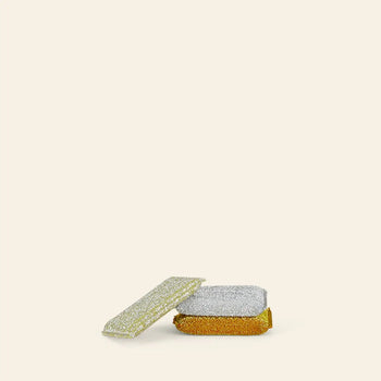 The Hawkins New York Lurex Sponges, Set of 3, includes gold, silver, and silver-and-gold sponges that bring a sparkling touch to your kitchen; all are stacked on a plain, light-colored background.