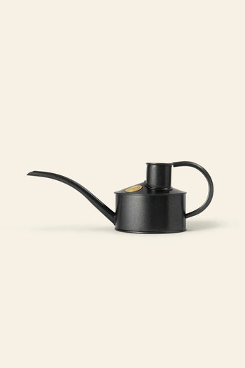The Haws The Fazeley Flow One Pint watering can by Haws features a stylish black metal design with a long, slender spout and curved handle, shown against a plain beige background.