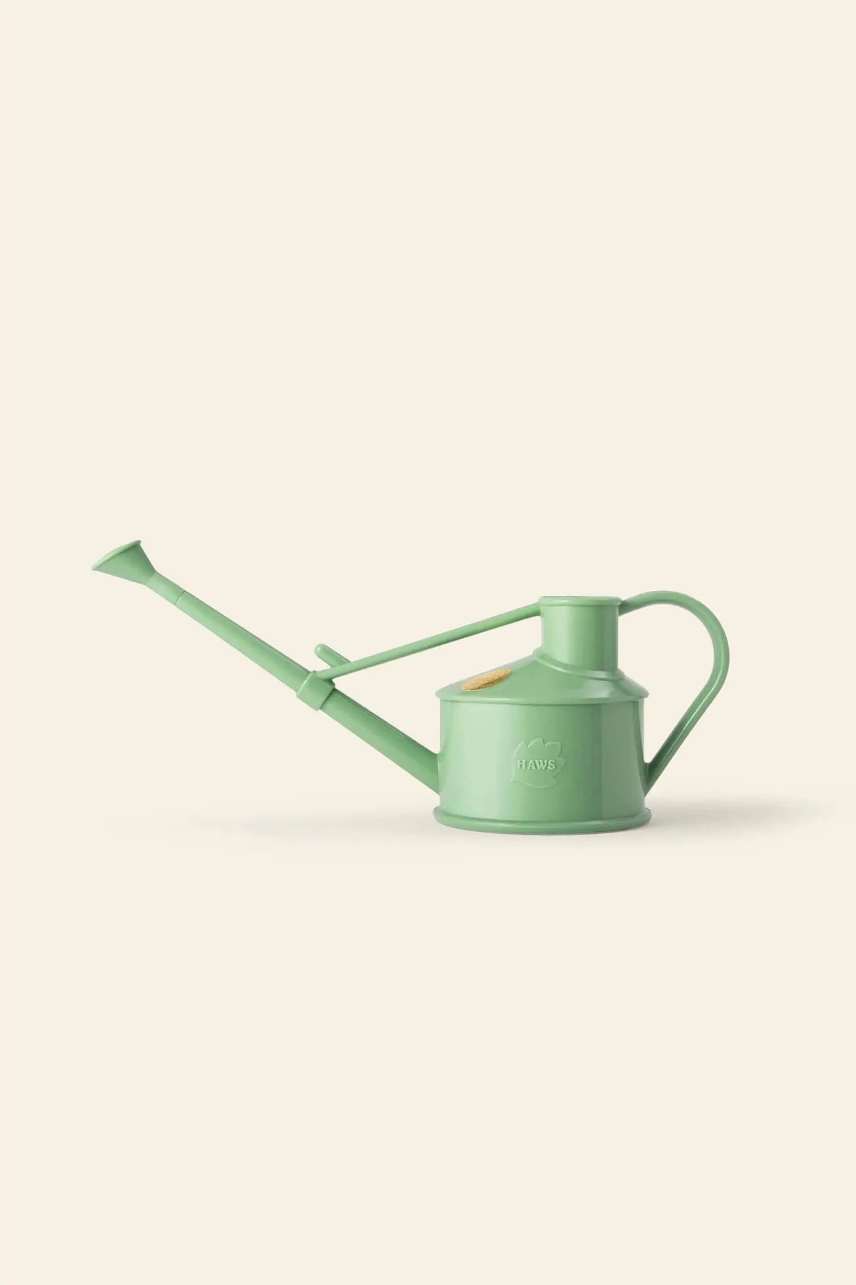The Haws The Langley Sprinkler, a light green metal watering can with a long spout and top handle, provides optimal water coverage and is displayed against a plain light beige background.