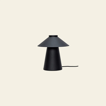 The Hübsch Chipper Table Lamp by Hübsch features a modern black design with a conical base and wide, flat shade. Positioned on a light beige background, it enhances ambiance while its power cord extends from the base.