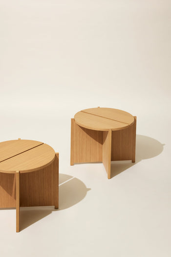 Two round Hübsch Dash Side Tables by Hübsch, made from FSC-certified wood with intersecting panel bases, are shown on a plain cream background with soft shadows—ideal for bringing minimalist style to any room.