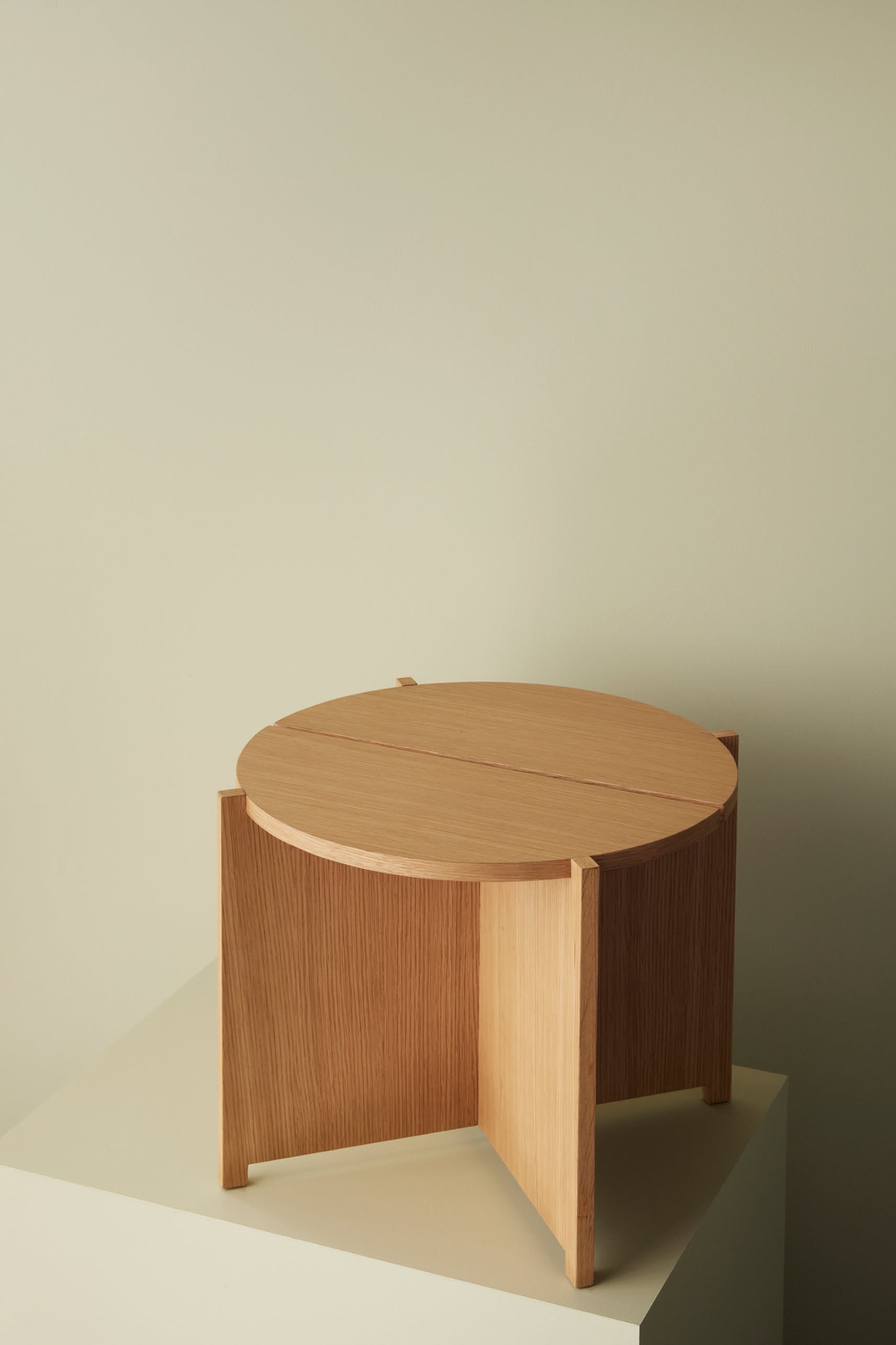 The Hübsch Dash Side Table by Hübsch, made from FSC-certified wood, showcases a minimalist design with three vertical panel legs and is shown on an off-white surface with a beige background for a modern look.