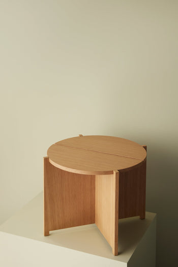 The Hübsch Dash Side Table by Hübsch, made from FSC-certified wood, showcases a minimalist design with three vertical panel legs and is shown on an off-white surface with a beige background for a modern look.