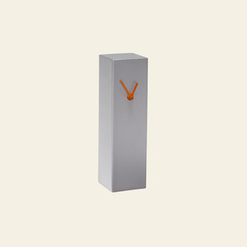 The Hübsch Hour Clock by Hübsch is a minimalist, rectangular gray timepiece with two orange hands forming a V shape on its front, highlighting its unique design against a plain light background.