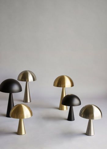 A set of Hübsch Mush Table Lamp Mini models by Hübsch in matte black, brushed brass, and silver finishes displayed on a light gray surface with a neutral background—offering stylish options for the modern home.