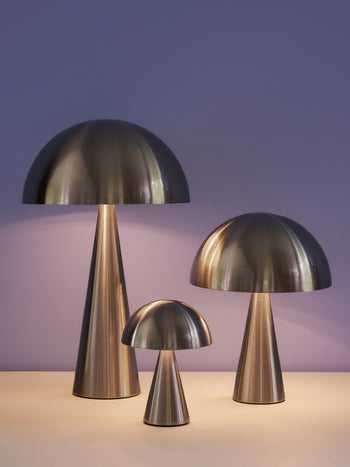 Three Hübsch Mush Table Lamp Mini lights of varying heights are displayed on a light surface with a soft purple background. Featuring conical bases and warm glow, these modern lamps by Hübsch come in multiple color options.