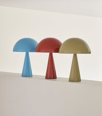 Three Hübsch Mush Table Lamp Minis in blue, red, and beige from Hübsch stand on a light ledge against a neutral background. Each lamp features a conical base and dome-shaped shade, making them perfect accents for any modern space.