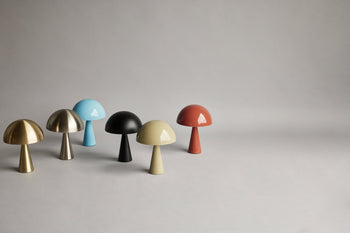 Six Hübsch Mush Table Lamp Mini lights by Hübsch in gold, silver, blue, black, beige, and red are displayed on a light gray surface with a neutral gray background—modern color options for any home.