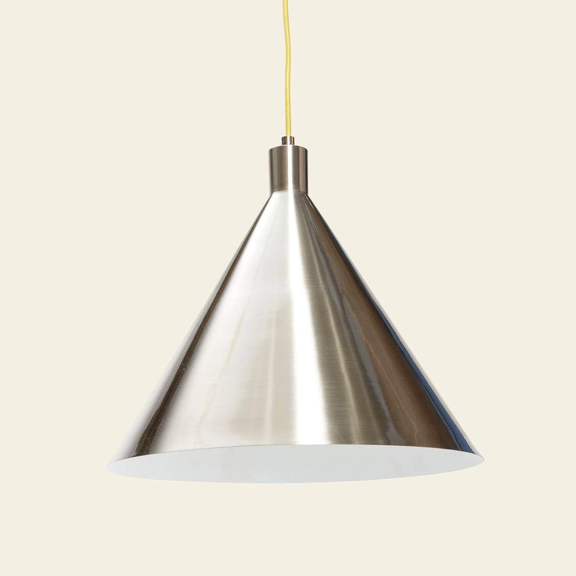 The Hübsch Yama Pendant by Hübsch features a metallic, cone-shaped design with a reflective finish, suspended from a yellow cord to bring modern elegance to any neutral setting.